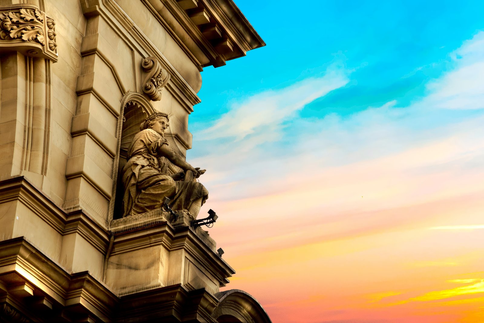 Detail eines klassischen Gerichtsgebäudes mit ornamentierten Säulen und Skulpturen, abendrot beleuchtet